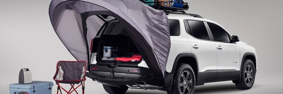 Three-Quarters Rear View of a White GMC Vehicle with the Rear Tailgate Open and a Tent Attached