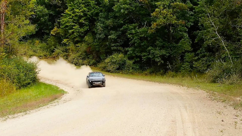 The HUMMER EV Pickup Truck Kicking up Dust as it Speeds Down a Dirt Road