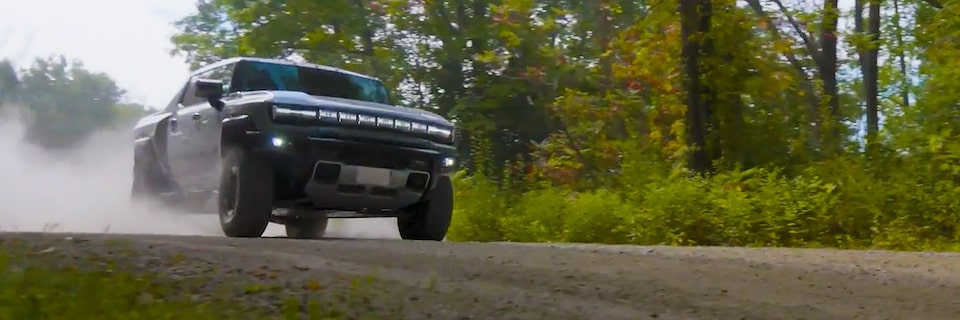 The HUMMER EV Pickup Truck Kicking up Dust as it Speeds Down a Dirt Road