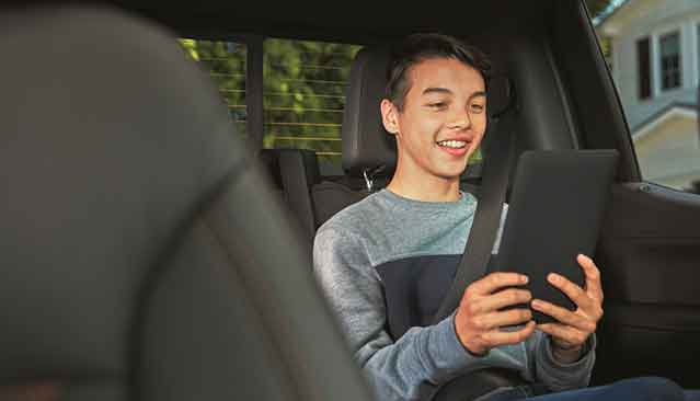 Smiling Child Using WarnerMedia Ride App on Compatible Device in GMC Vehicle