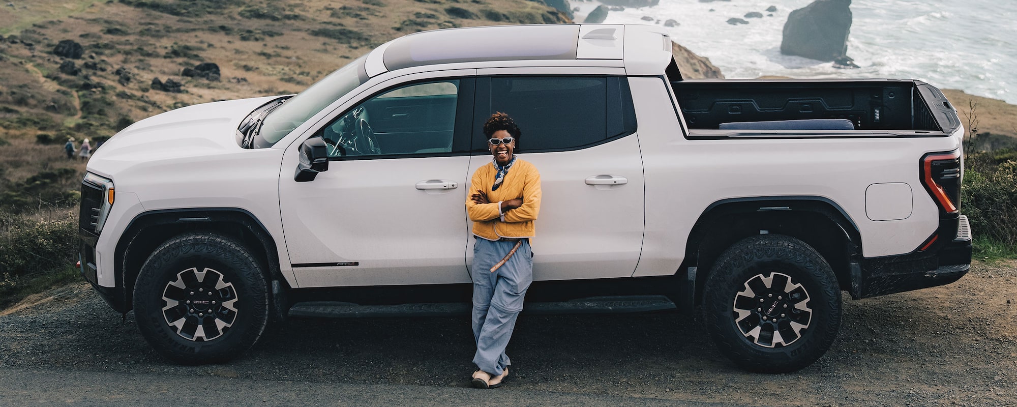 L. Renee Blount Stands Next to a White GMC Truck Overlooking a Rocky Ocean Coastline