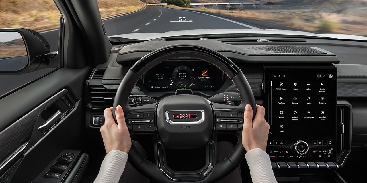 Driver's Hands on the Steering Wheel of a GMC Vehicle with Adaptive Cruise Control Activated Showing 55 MPH on the Head-Up Display