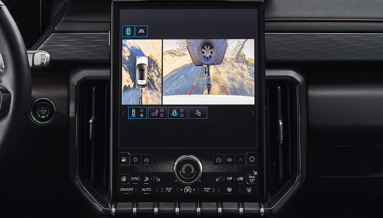 GMC Infotainment Screen Showing a Detailed Hitch View of a Trailer Hitch Being Connected to a Receiver on a Dirt Road
