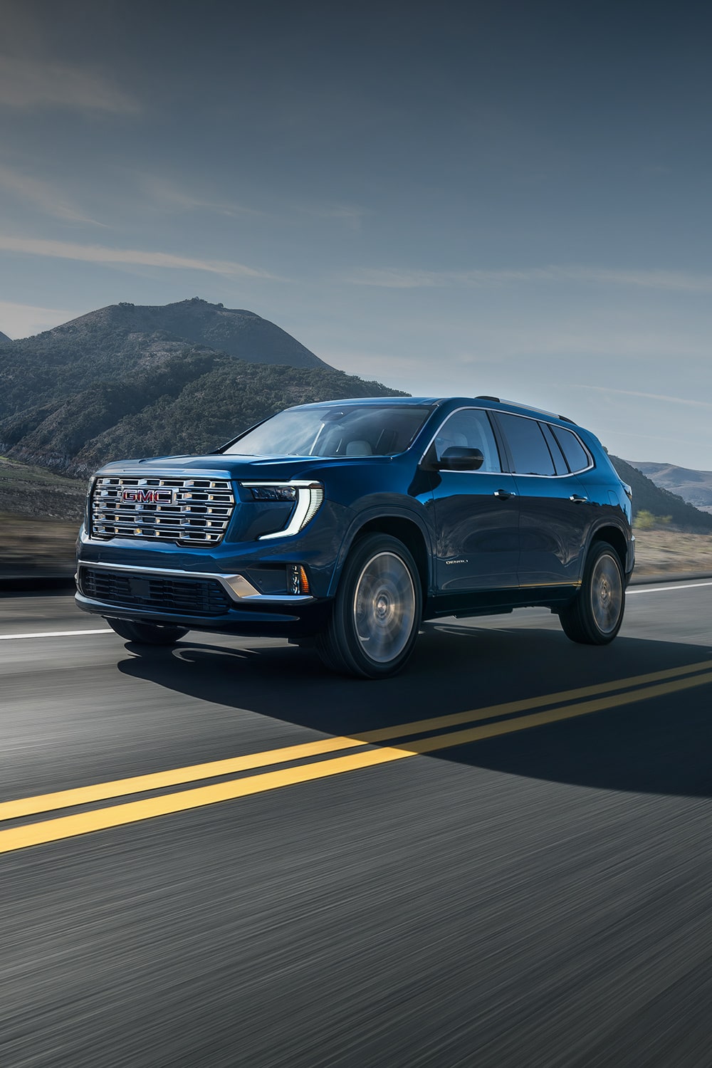 Dark Blue GMC Acadia SUV Driving Down a Scenic Mountain Road with a River in the Background