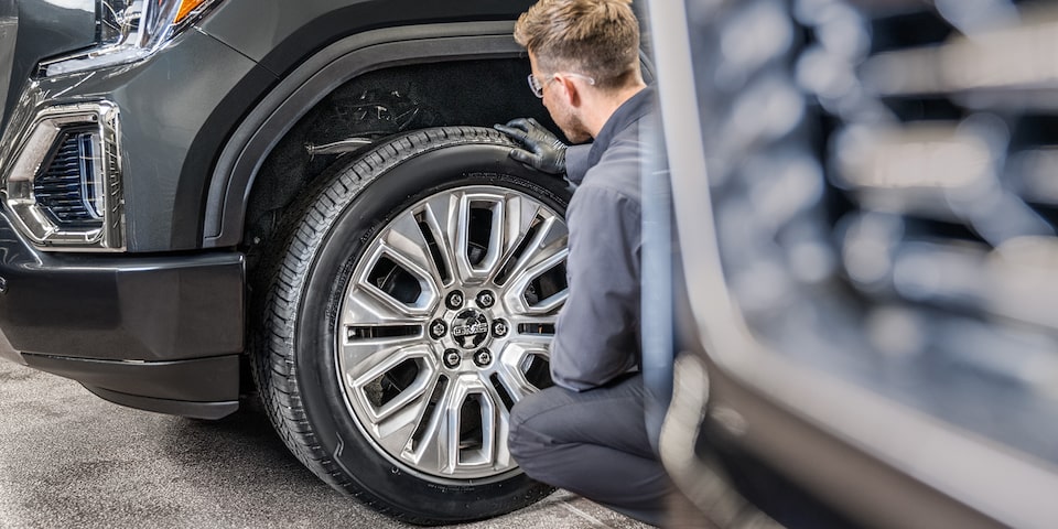 GMC Certified Service Technician Inspecting a Wheel on a Vehicle