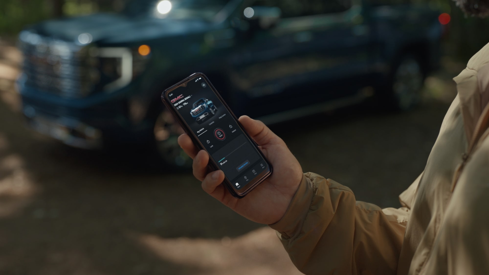 A Person Holding Their Smartphone While Using the myGMC Mobile App.