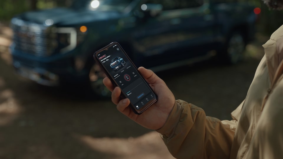 A Person Holding Their Smartphone While Using the myGMC Mobile App.