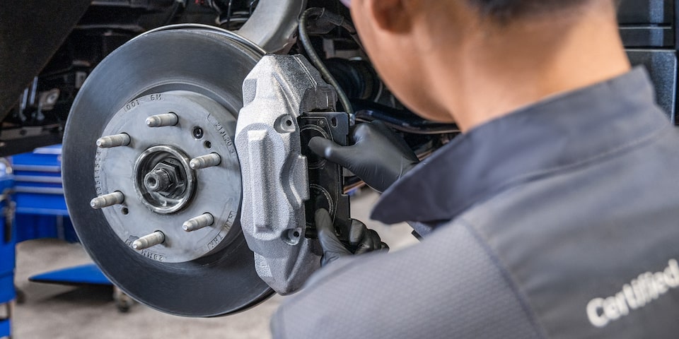 A Mechanic Wearing Safety Glasses Inspecting the Break of a Wheel inside a Vehicle