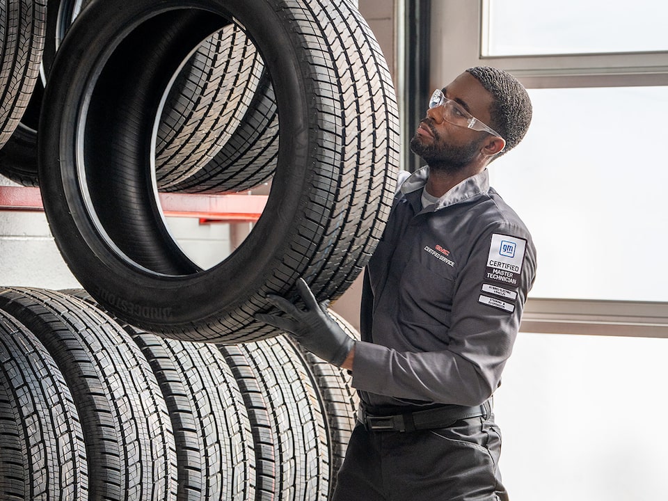 A Man Is Picking Up a Tire and Putting It up in a Set