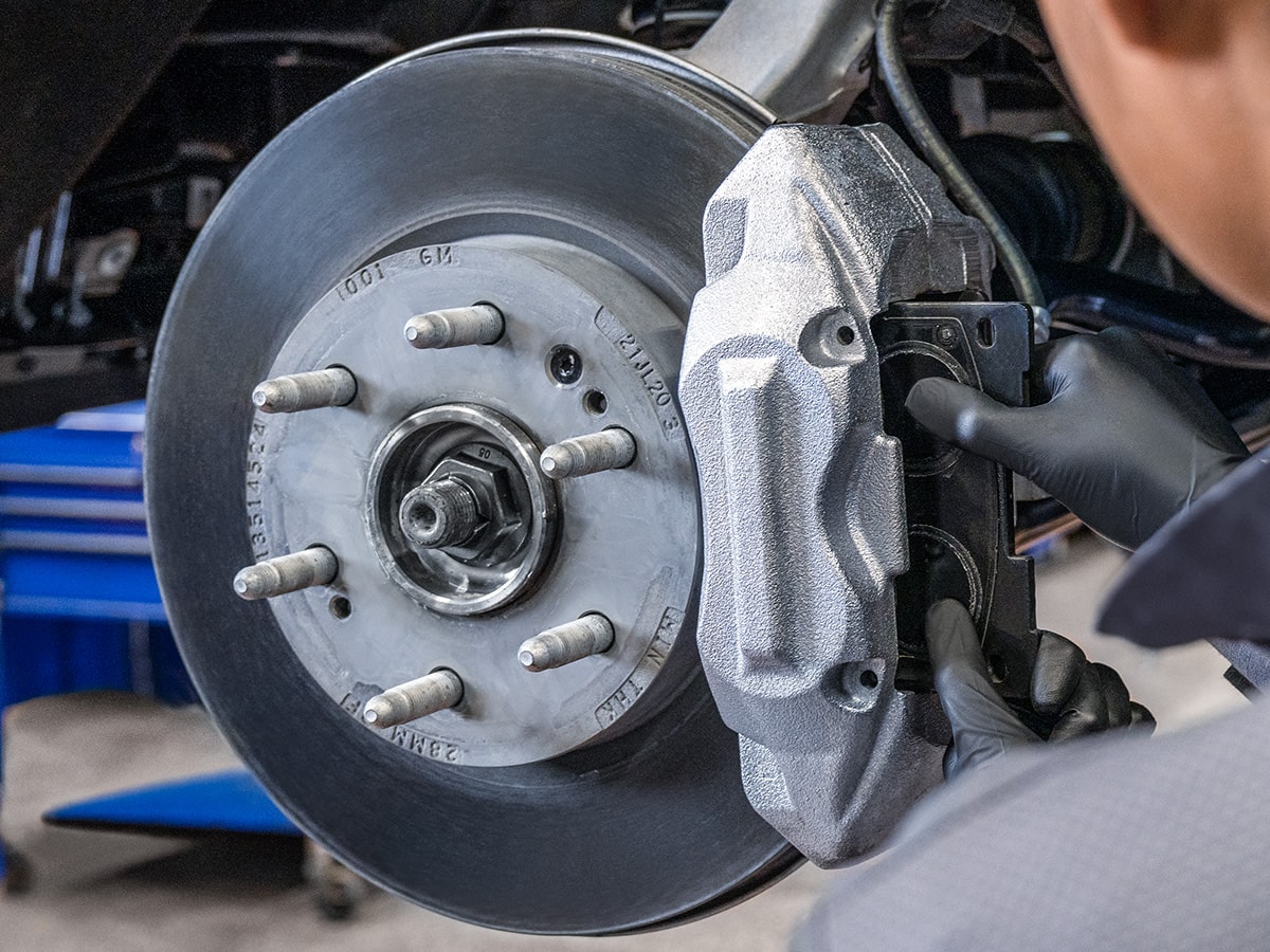 A Mechanic Wearing Safety Glasses Inspecting the Break of a Wheel inside a Vehicle