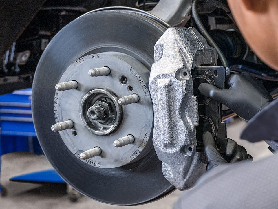A Mechanic Wearing Safety Glasses Inspecting the Break of a Wheel inside a Vehicle