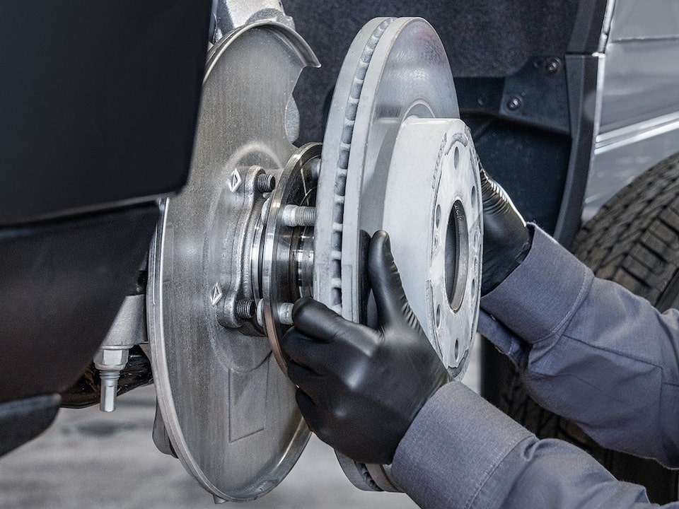 A Mechanics Hands Are Seen Placing a Metal Break Rotor for a Vehicle