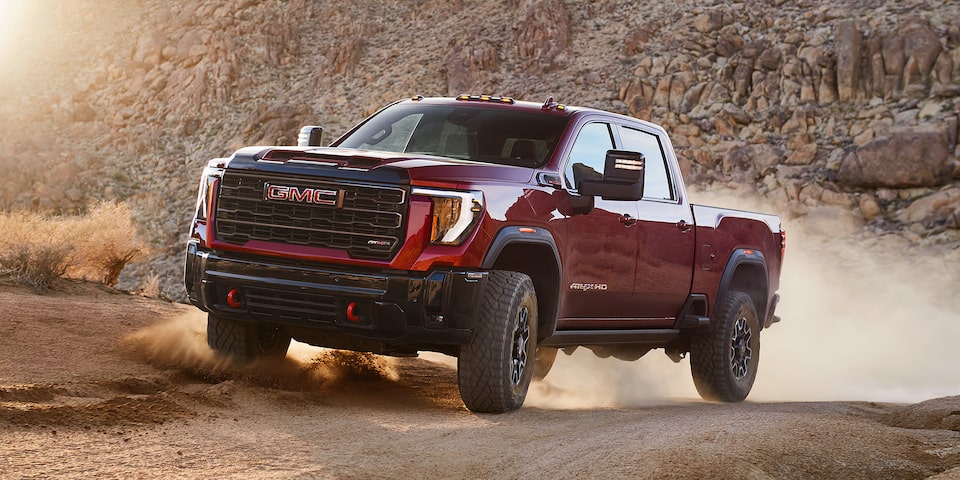Three Quarters View of a Red GMC Pickup Truck Going Down a Desert