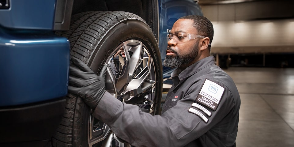 A Certified Technician Installing a New Tire on a Raised Vehicle