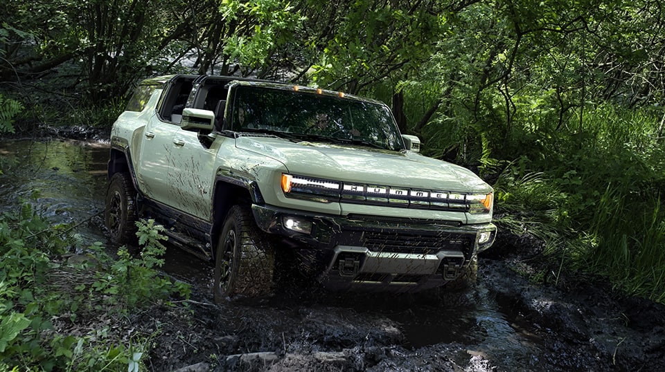 A Hummer EV Driving Off-road Through Mud