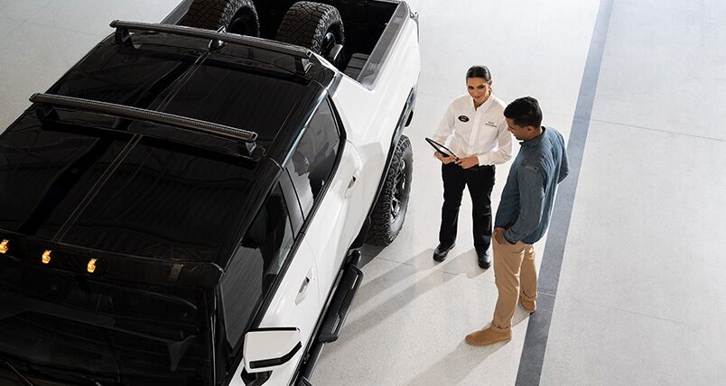 GMC Certified Service Representative Speaking with a GMC Hummer EV Trucker Owner Outside Their Vehicle