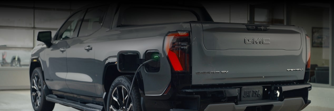 A Rear View of a GMC Sierra EV in a Dealership Room While Getting Charged.