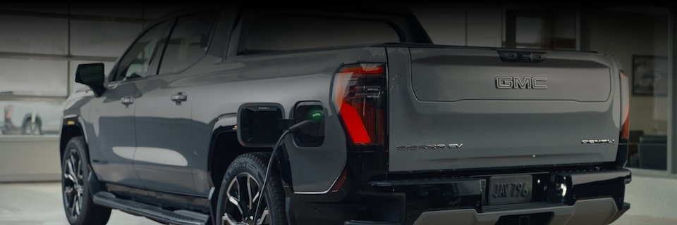 A Rear View of a GMC Sierra EV in a Dealership Room While Getting Charged.