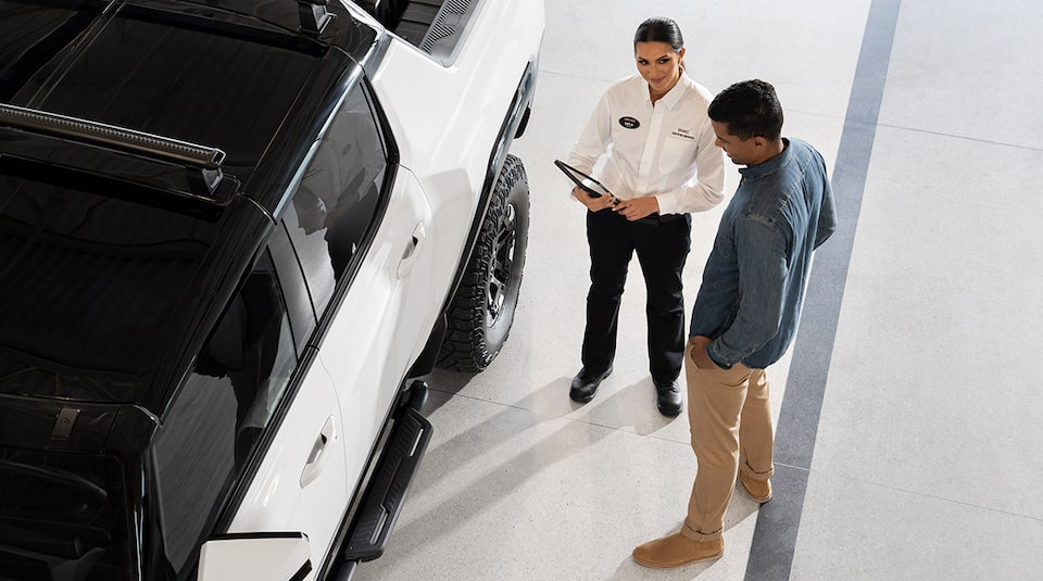 GMC Certified Service Representative Speaking with a GMC Hummer EV Trucker Owner Outside Their Vehicle