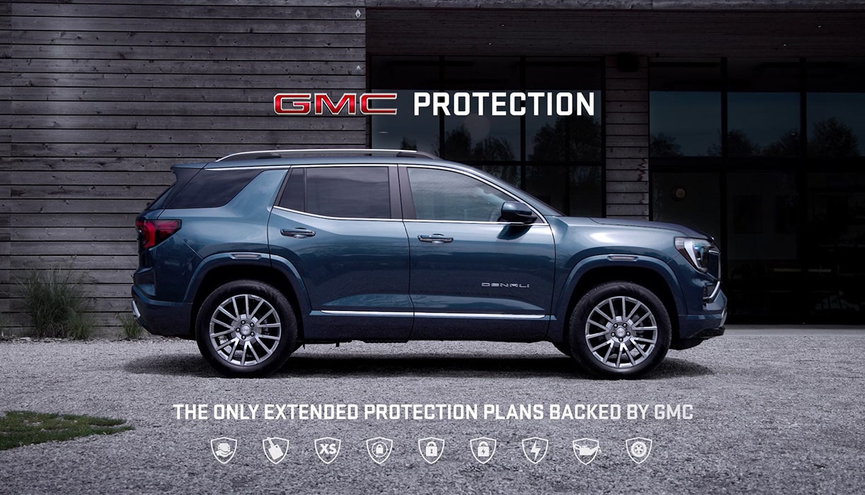 A Man in His Gargage with a Work Apron on Looking Downward and a GMC Truck Behind Him