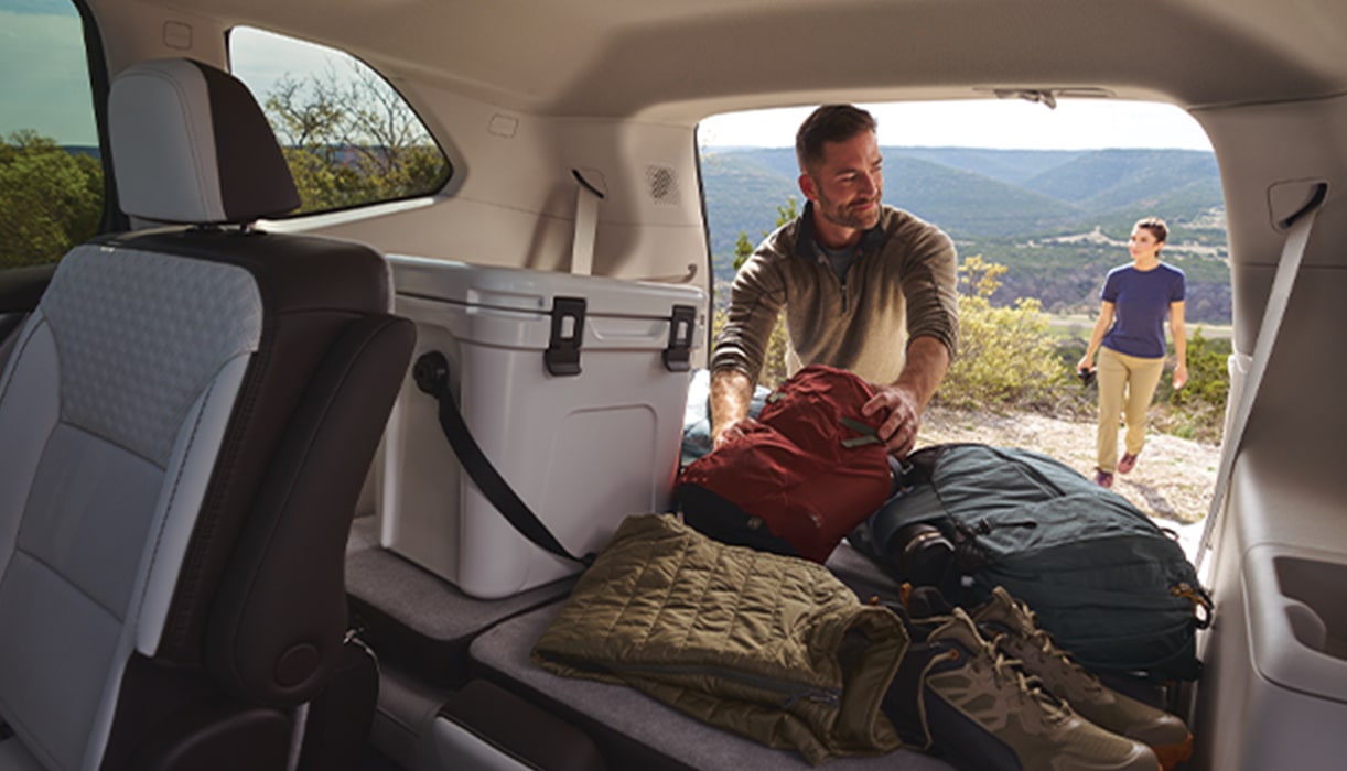 Couple Loading Camping Equipment Into GMC SUV Rear