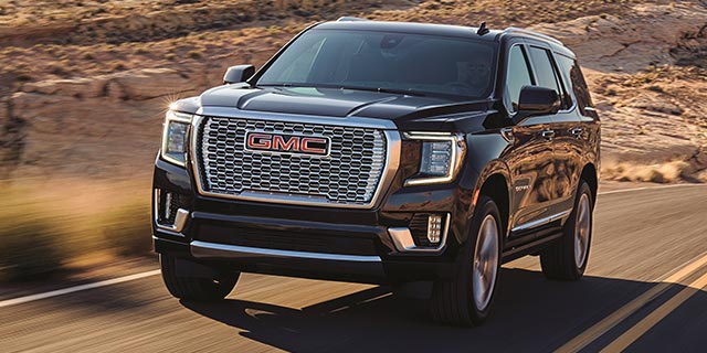 2021 GMC Yukon Denali driving on two-lane road through rugged terrain
