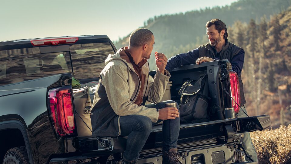 Men Sitting in Bed of GMC Sierra Truck with Hiking Gear