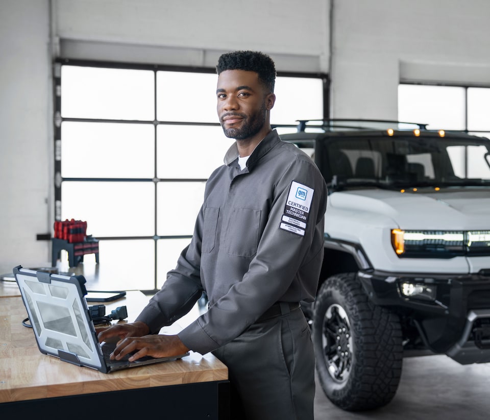 Employee next to car on laptop