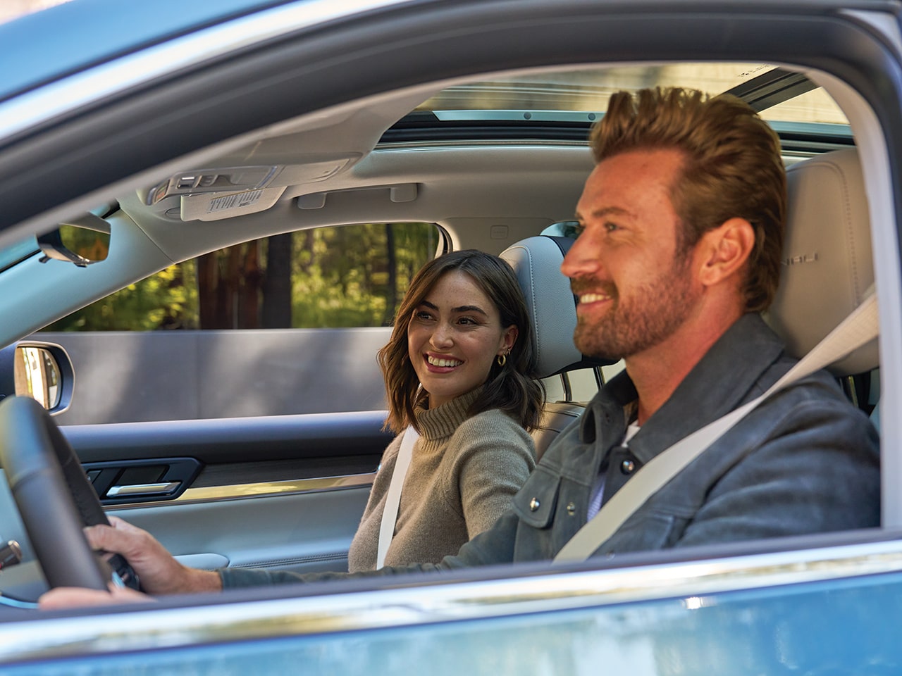 A Man and a Woman Smiling in the Front Seats of a GMC Vehicle with a Sunroof