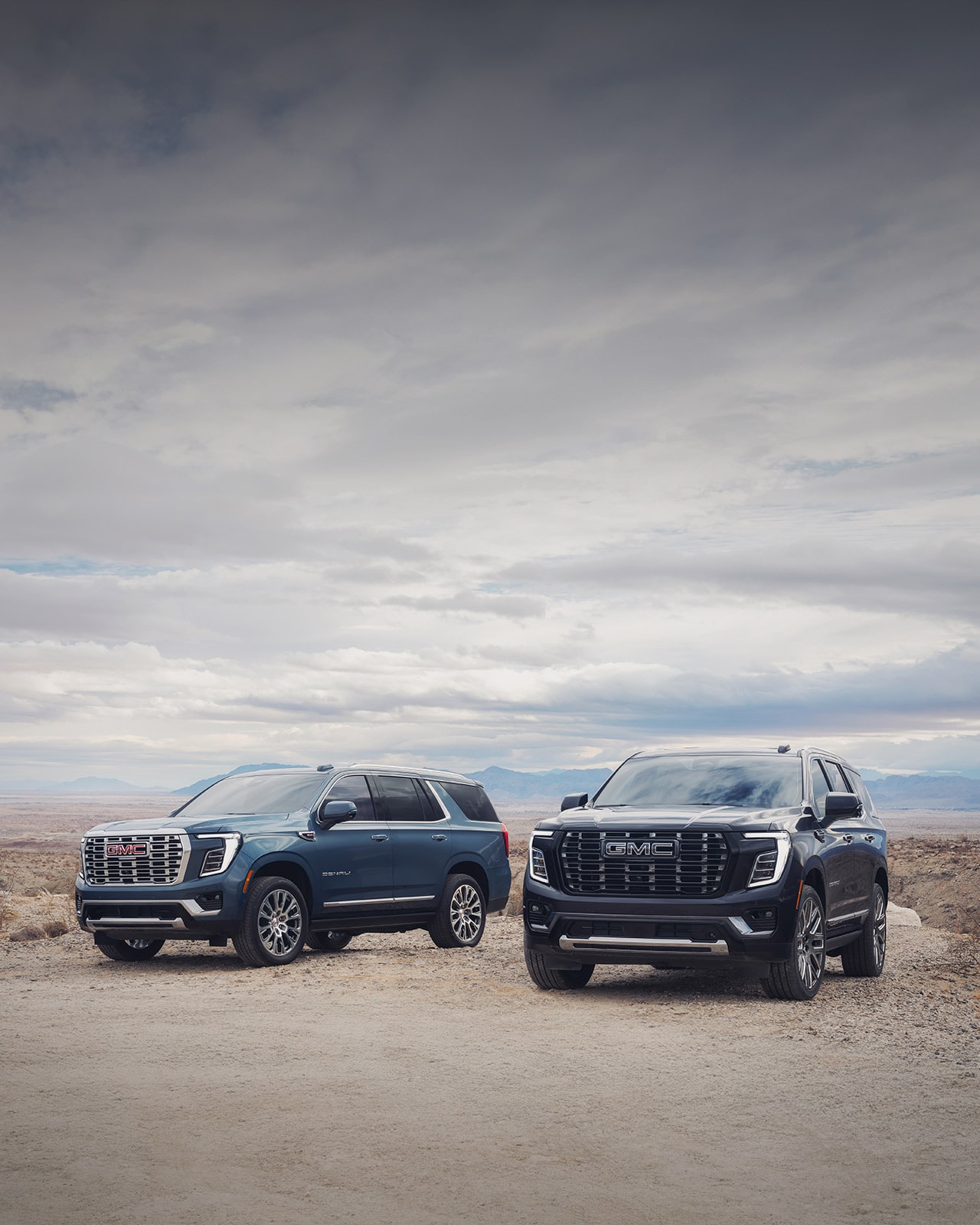 GMC SUVs Parked Side by Side in a Desert with Blue Skies in the Distance