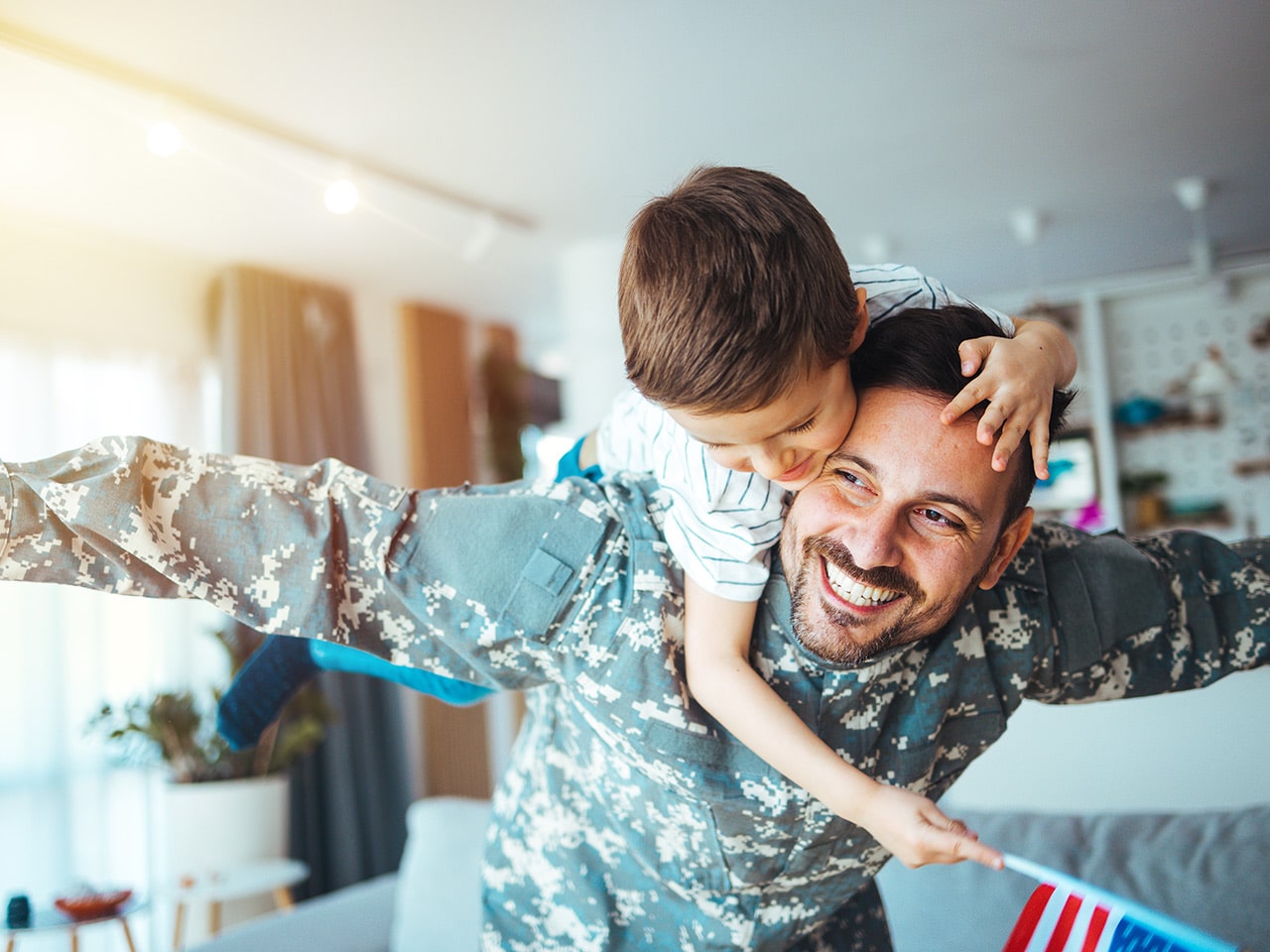 A Smiling Father in a Military Uniform Giving a Piggyback Ride to a Young Child