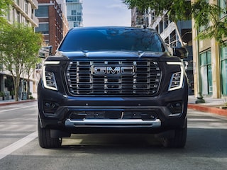 A Dark Blue GMC Yukon SUV Driving Head on in the Middle of a City Street