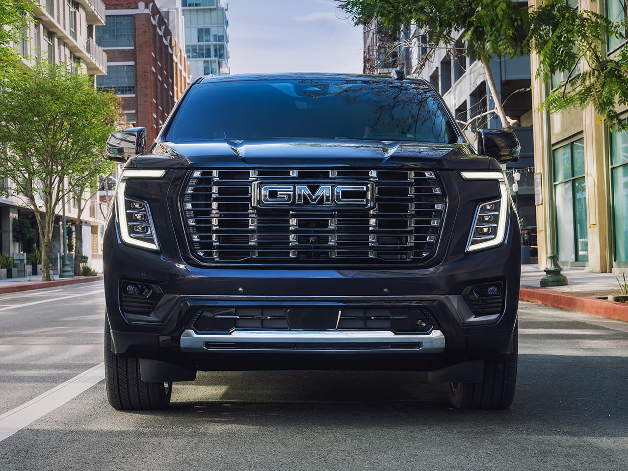 A Dark Blue GMC Yukon SUV Driving Head on in the Middle of a City Street