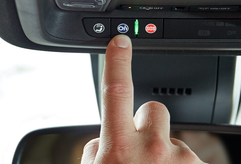 Driver Pressing OnStar Services Button in GMC Vehicle 
