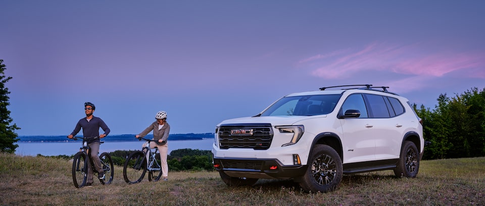 Man and woman riding bikes past GMC vehicle