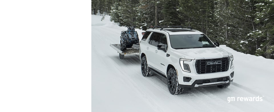 white GMC pulling snowmobile