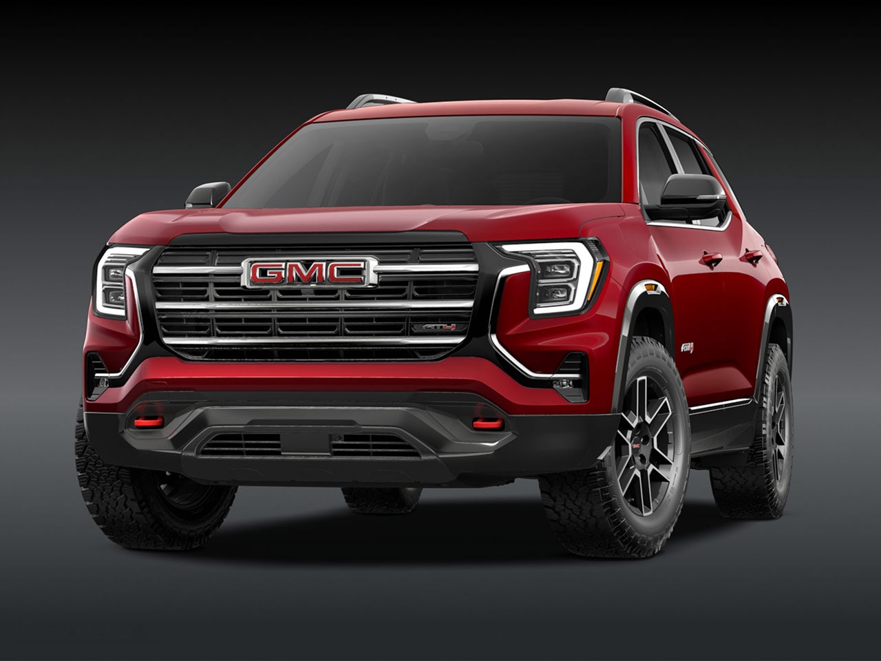 A Front Exterior View of a Bold Red GMC AT4 SUV with a Prominent Grille Headlights and Rugged Tires