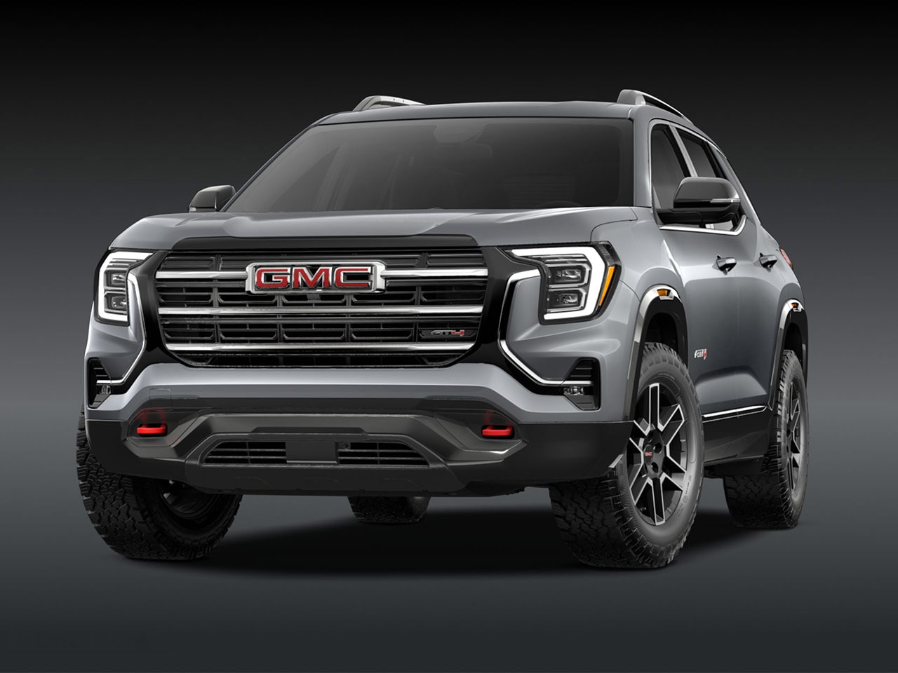 A Front Exterior View of a Sleek Silver GMC AT4 SUV with a Prominent Grille Headlights and Rugged Tires