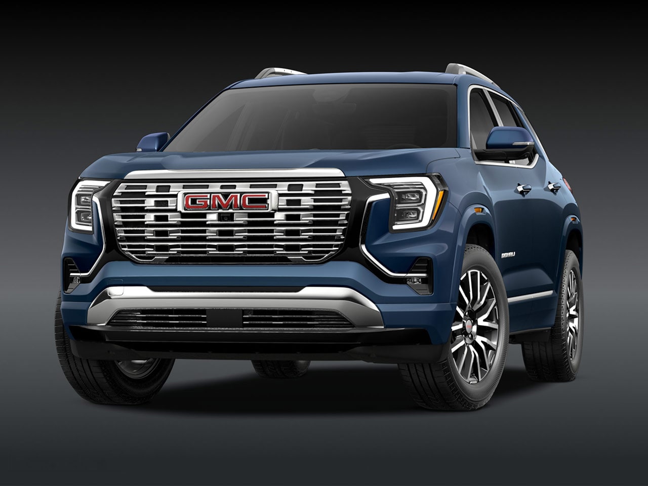 A Front Three-Quarter View of the Dark Blue 2026 GMC Denali SUV on a Dark Background