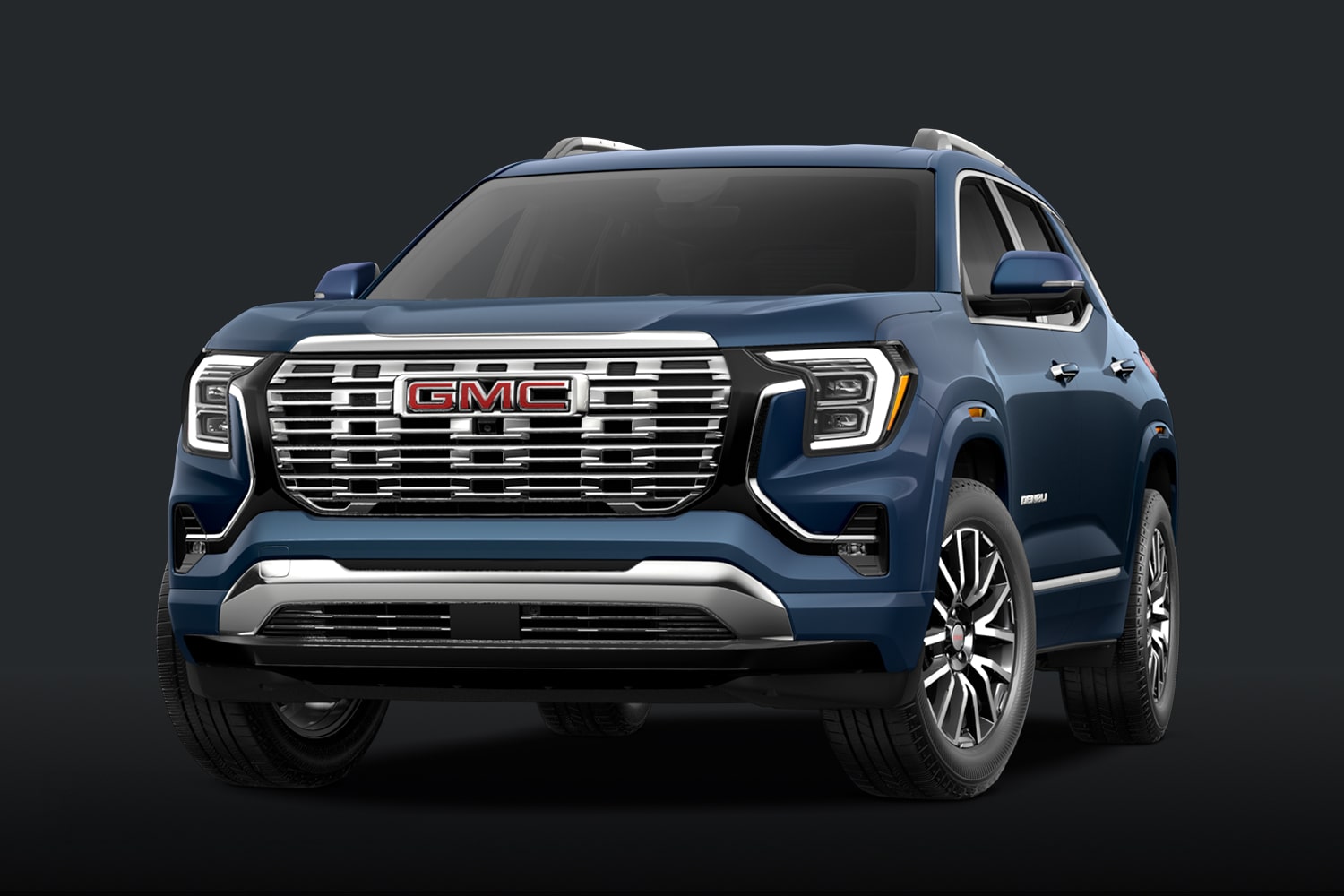 A Teal Blue GMC Denali SUV With a Chrome Grille Against a Dark Background