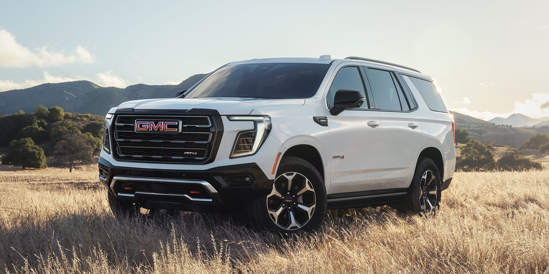 Front Three-Quarters View of the GMC Yukon AT4 Full-Size Off-Road SUV Parked on a Scenic Field