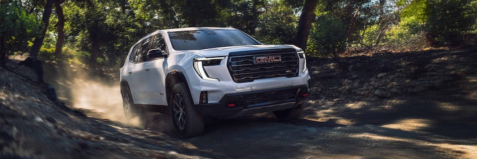 A GMC Acadia AT4 SUV Driving on a Dirt Path Through the Trees
