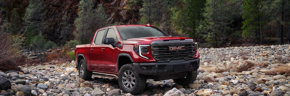 A GMC Sierra AT4 Truck Driving on a Rocky Path Surrounded by Trees