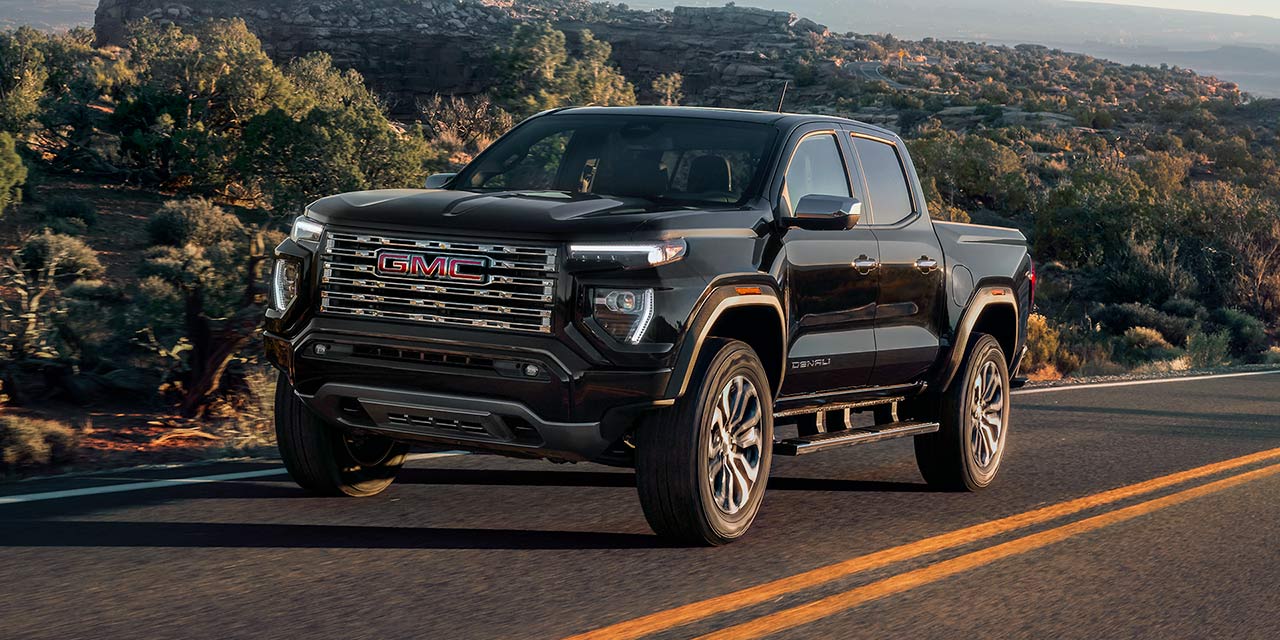 Front Three-Quarters View of the GMC Canyon Mid-Size Truck Parked in the Desert with a Beautiful Sunset Sky Above