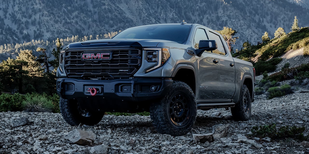 The GMC Sierra 1500 Pickup Truck Parked on a Grassy Hill as the Sunlight Shines Down on the Blue Truck