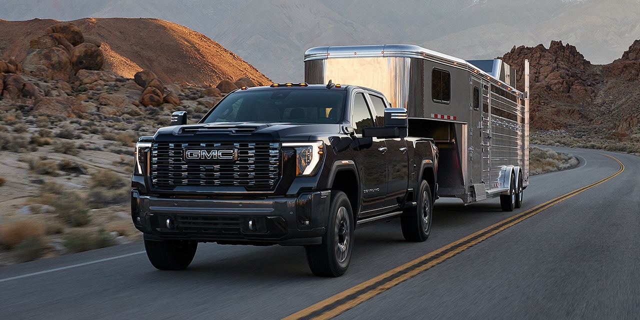 The GMC Sierra HD Heavy Duty Truck Driving Down the Road Towing a Trailer