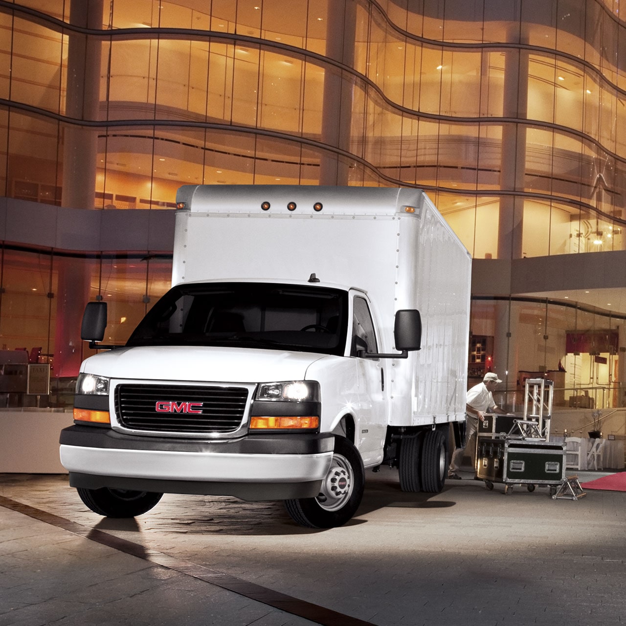 Front Three-Quarters View of the GMC Savana Cutaway Van Parked in Front of a Large Building