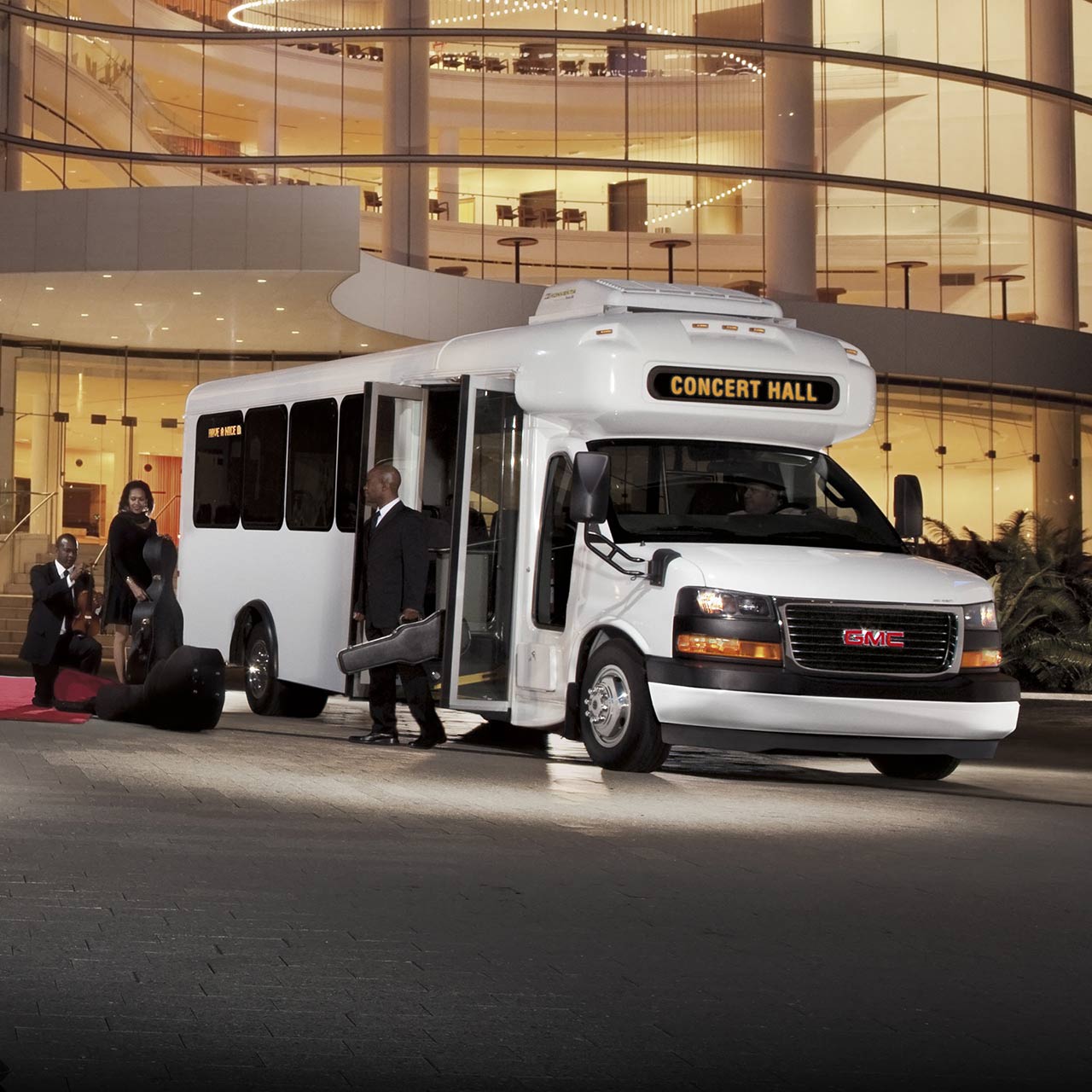 Front Three-Quarters View of the GMC Savana Cutaway Van Parked in Front of a Large Building