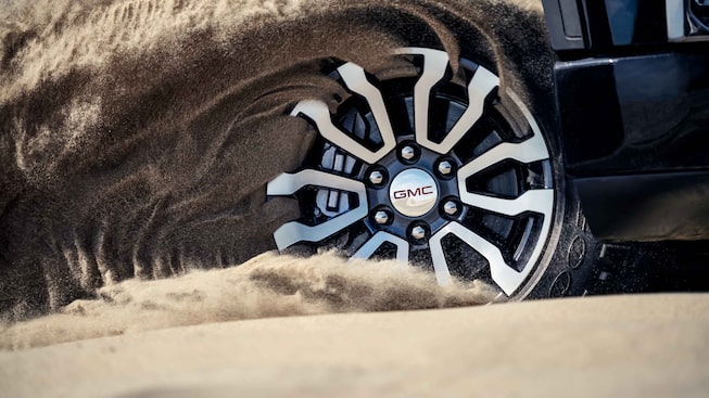 2021 GMC Sierra 1500 AT4 Off-Road Truck wheels driving on sand close up