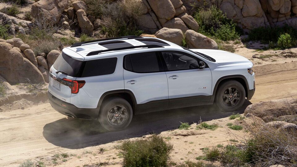 The Summit White GMC Acadia Driving Off-Road Kicking Up Dust in the Desert